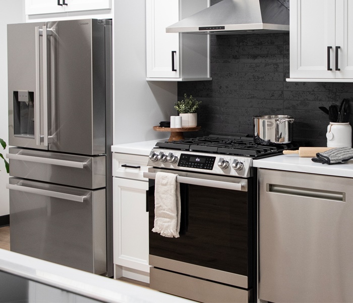 Kitchen containing a suite of appliances including stainless steel refrigerator, oven range and dishwasher. 